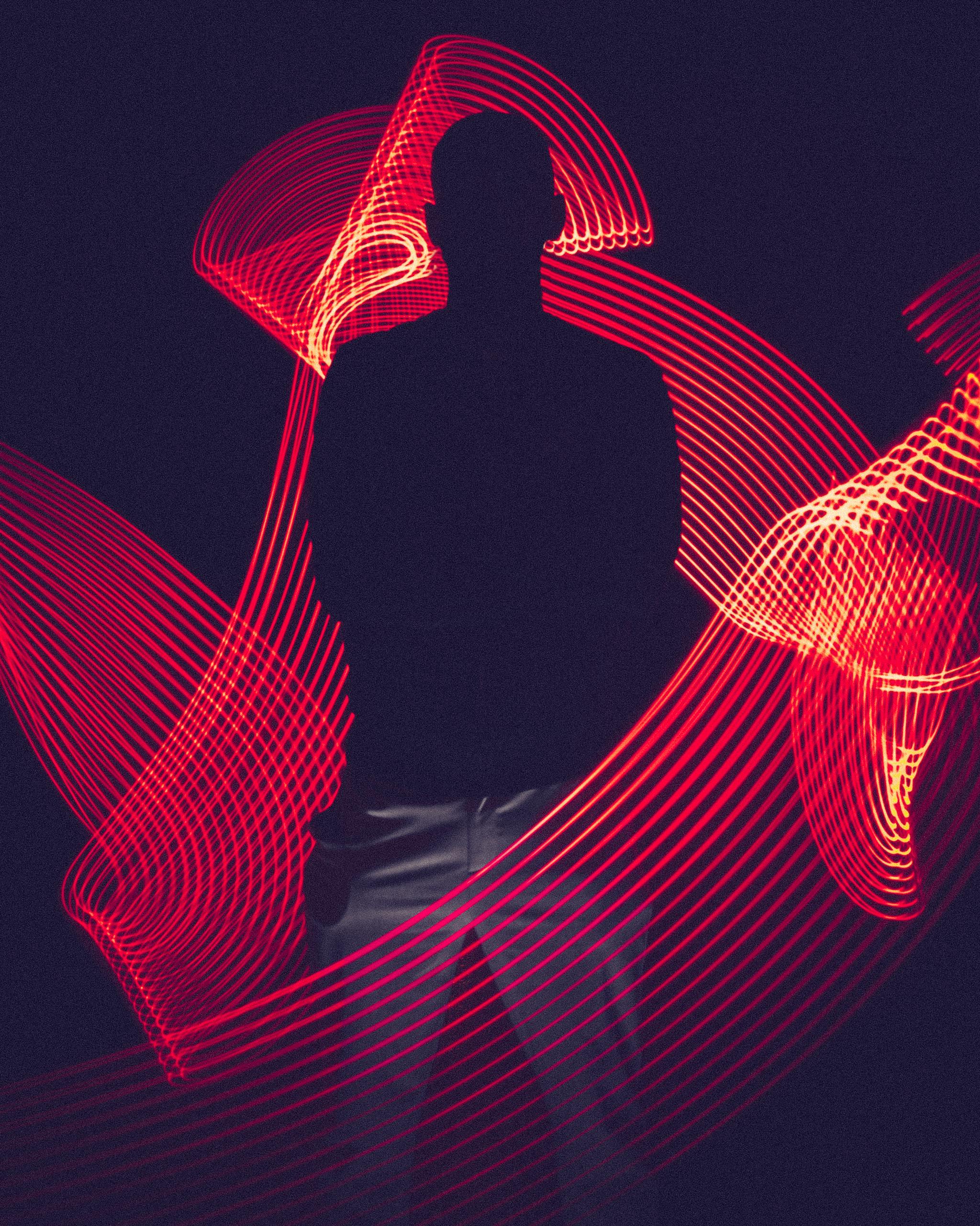 Home 3 A silhouette of a person surrounded by artistic red light trails, creating a dynamic visual effect.