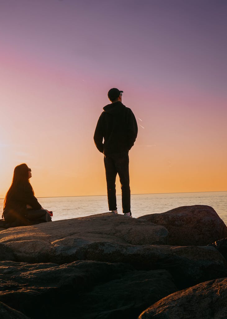 Sobre Nosotros 1 Two people enjoy a peaceful sunset on Batumi's rocky coast, embodying tranquility and connection.